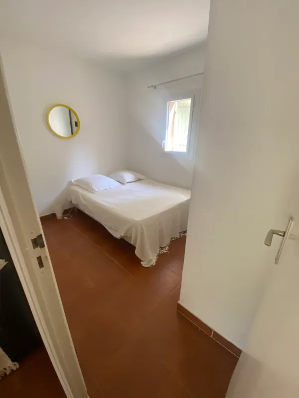 La chambre : lit double, murs blancs et sol en tomettes
