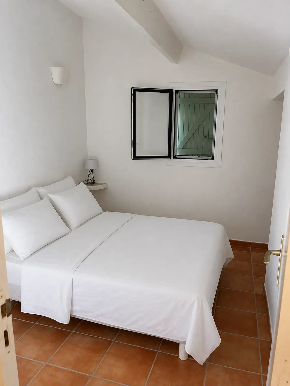 La chambre : lit double, murs blancs et sol en tomettes